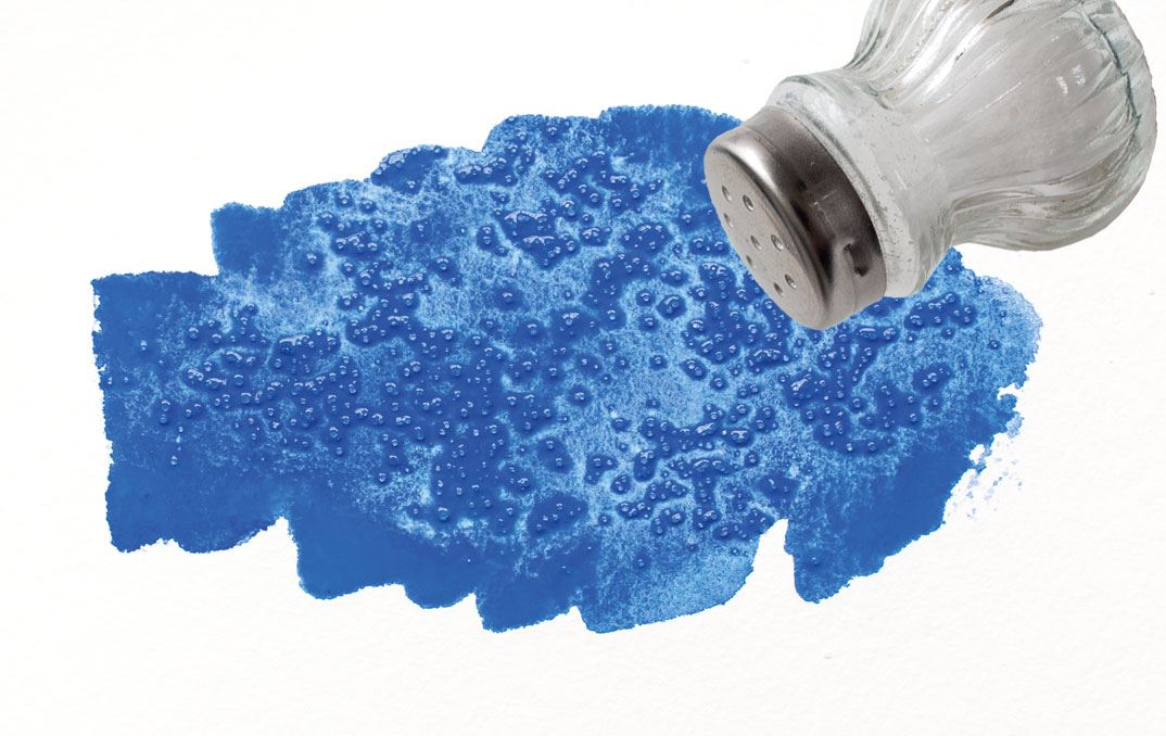 A salt sprinkler sprinkling salt on a blue blotch of paint.